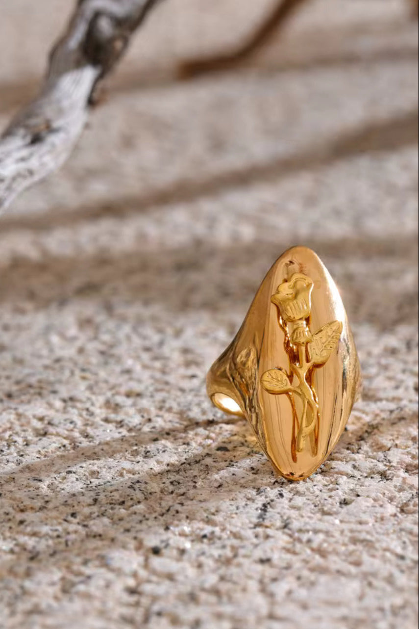 Gold ring with a floral design on a textured surface. One size 18K gold flower ring – adjustable stainless steel jewelry for women.