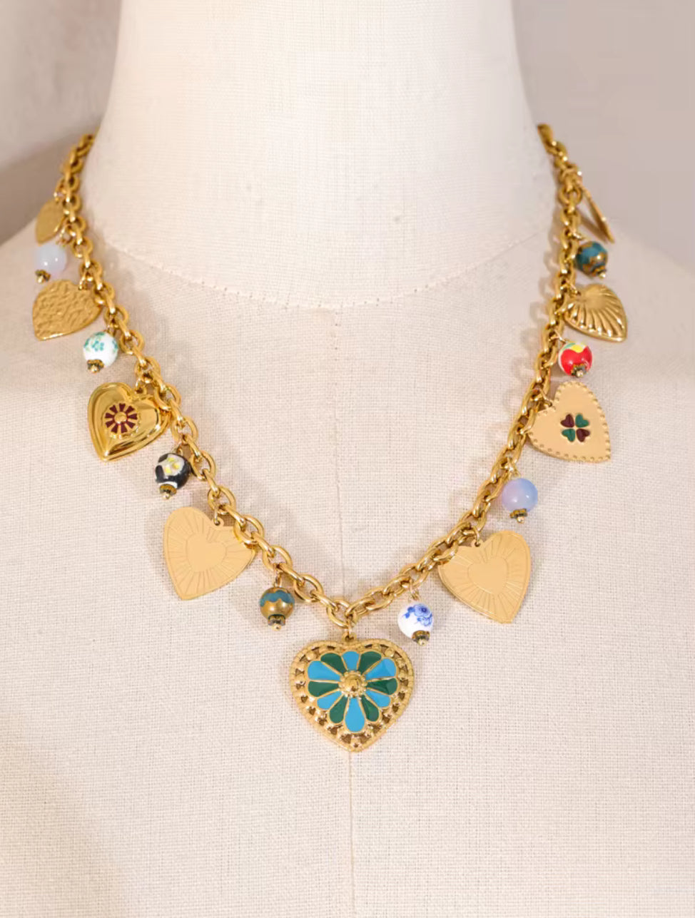 Gold necklace with heart-shaped charms on a mannequin.  18K gold-plated necklace

hypoallergenic necklace

tarnish-free jewelry

gold chain for women

beach necklace

dainty necklace

layering necklace set

trendy women’s accessories

jewelry for moms.