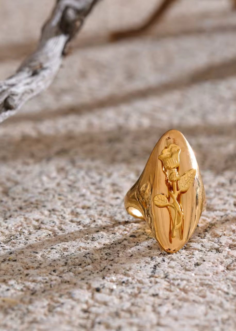 Gold ring with a floral design on a textured surface. One size 18K gold flower ring – adjustable stainless steel jewelry for women.
